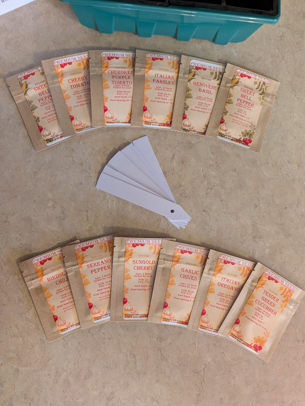 Seed packets on a beige surface with a teal container in the background.